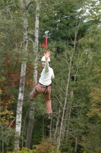 Photo of Krista riding the zipline at Camp Bryn Mawr in Wayne County, PA on team building day.