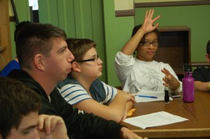 Photo of young Manor Ink newspaper staff at the library in Livingstin Manor, NY in the Sullivan County Catskills practicing interviewing skills, arts based research and engagement journalism.